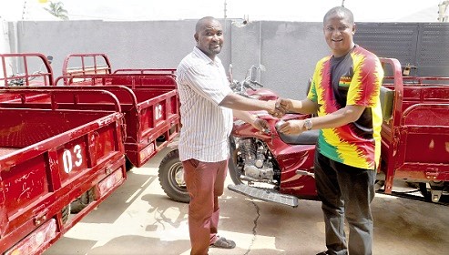 Mohammed Adamu Ramadan (right) presenting the keys of the tricycle to Mr Jacob Mensah, a businessman
