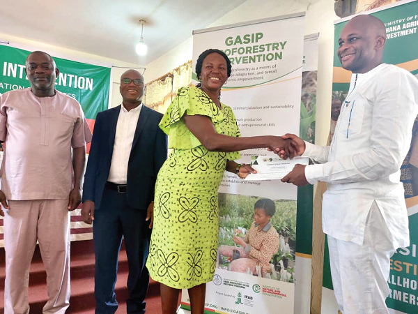 Nicholas Soyiri (right), Jirapa MCE, presenting a certificate to one of the beneficiaries, Lovia Kooun, during the ceremony