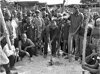 Bismark Tetteh Nyarko (with pickaxe), MP for Upper Manya Krobo Constituency, cutting the sod for work to commence. Looking on are some residents of Sekesua