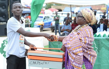  Nanabaa Ayaw Osabarima (right), Tufohemaa of Amanase, presenting a set of tools to Kofi Yirenkyi, a beneficiary, at the ceremony at Suhum