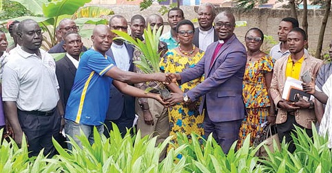 Rev. Dr Seth Kissi (right), Chairman of the Akuapem Presbytery of the Presbyterian Church of Ghana, presenting seedlings to William Antiri Obuobi, one of the beneficiaries. Looking on are some church members