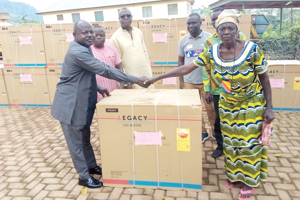 Charles Oware-Tweneboah (left), District Chief Executive for Fanteakwa North, presenting a deep freezer to Teiko Teye, a 65- year-old woman