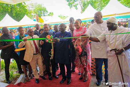 Dr Mahamudu Bawumia (middle) being assisted by other officials and guests to cut the tape to inaugurate the office.