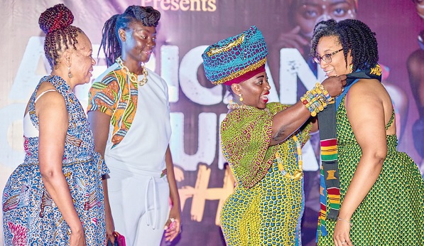 • Patricia Lawton (right), leader of the delegation, being decorated with a Kente sash by Akumaa Mama Zimbi, a broadcast journalist with the Multimedia Group, while some team members look on