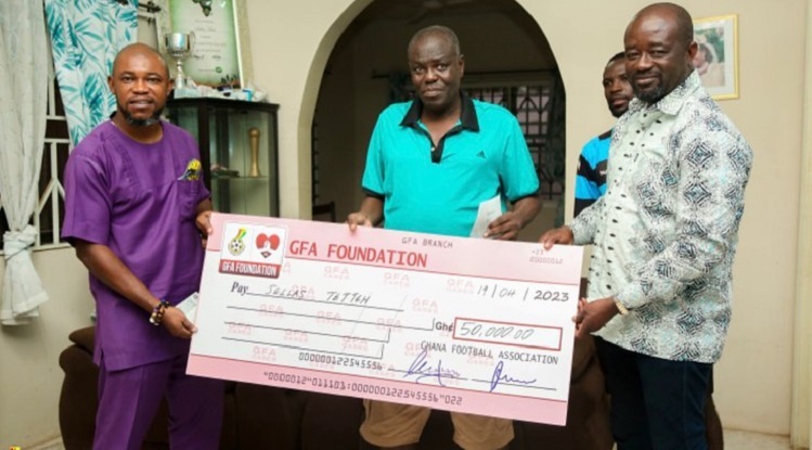 Coach Sellas Tetteh receiving a dummy cheque from GFA President, Kurt Simeon-Okraku