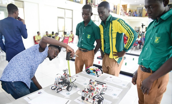 Kojo Anyinam Boateng (left), Executive Judge of the competition, measuring the size of a robot for students of Prempeh College