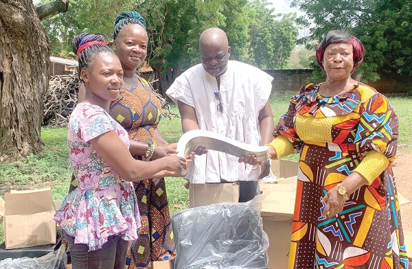 Vida Anaab (right), Builsa North MCE,  presenting an equipment to one of the beneficiaries