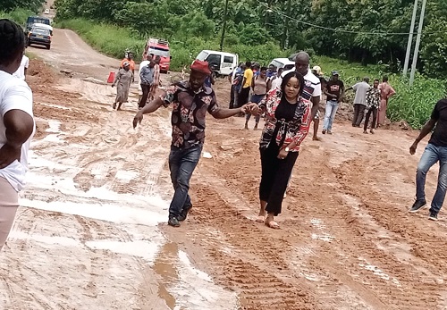  Betty Krosby Mensah (arrowed), MP for Kwahu Afram Plains North, being assisted to navigate her way through the muddy road
