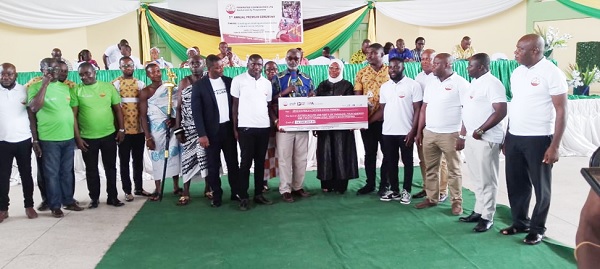 Adamu-Zibo (arrowed), Managing Director of FEDCO, presenting a dummy cheque to representatives of the cocoa farmers during the meeting at Assin Fosu. With her are some of the district officers of FEDCO