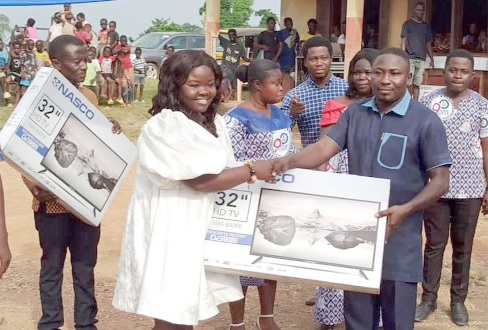 Elder Asare Brew presenting a TV set to one of the beneficiaries