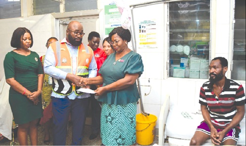 Martin Afram (2nd from left), Director of Planning and Programmes, NRSA, presenting the amount to Dora Naa Adei Kotey for the bills of Michael Avisey(right).