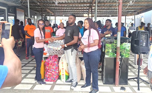 Augustina Amoah (left), the group leader for the September borns, presenting some of the items to James Anchebah (2nd from right), a supervisor at the centre