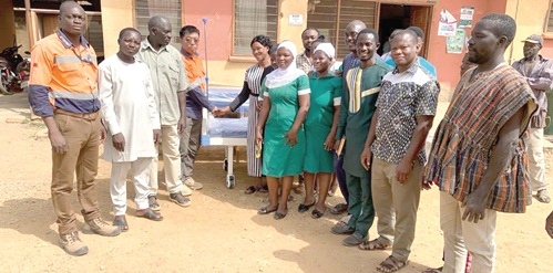 Feng Baoli (4th from left), the Vice President of Cardinal Resources Ghana Limited, presenting  the beds to Agnes Anamoo, the District Chief Executive for Nabdam District, while staff of the health facility look on