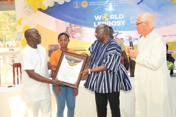 The Vice President, Dr Mahamudu Bawumia (2nd from right), being assisted by Osei Assibey Antwi (left), the NSS Executive Director,  to present the citation to Donna Elikplim Agbeshie (2nd from left), while Rev. Fr Andrew Campbell looks on
