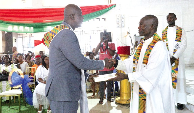 Very Rev. George Arthur (right), Chaplain General of the Ghana Police Service, presenting a Bible to Chief Inspector Samuel Danso Marfoh during the induction ceremony