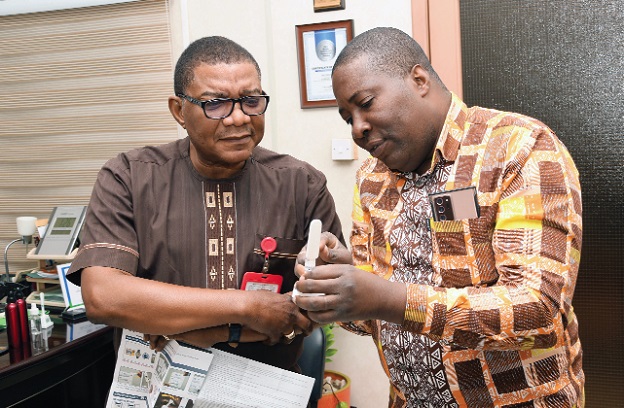 Dr Stephen Ayisi Addo (right), Progamme Manager for National STIs and HIV/AIDS Control Programmes, demonstrating the use of the HIV/AIDS test kit to Kobby Asmah, Editor, Graphic, when he paid a courtesy call on him. Picture: EBOW HANSON