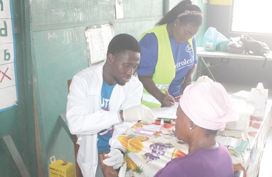 Gideon Tettey-Gah (left), a Medical  Laboratory Technician, examining a beneficiary of the health screening. Picture: ESTHER ADJEI