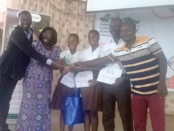  Frederick Ken Appiah (left), Deputy Director of the Energy Commission, being assisted by Irene Owusua (2nd from left), Eastern Regional Director of Education, to present a memento to Okuapeman SHS for winning the competition