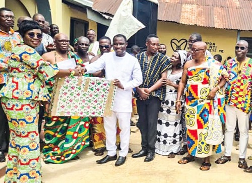 Abena Gyamera, Abuakwa North Director of Education, presenting the first prize of a television set to Samuel Acheampong, the winner of the maiden Ati Best Teacher Awards Scheme. Looking on are some chiefs and  teachers from the community