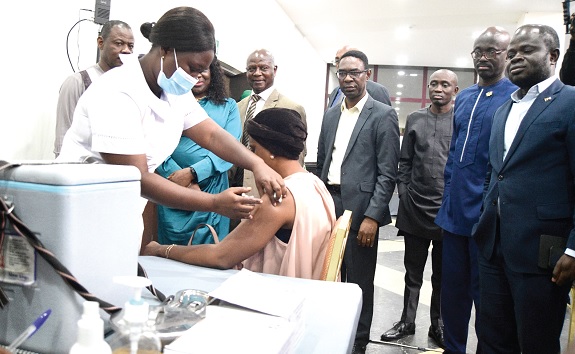 A woman receiving a COVID-19 jab from a health official at the launch. Looking on is Dr Patrick Kuma-Aboagye (left behind) and some officials. Picture: EMMANUEL QUAYE 