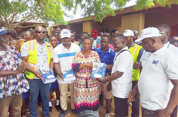 Yaw Antwi-Dadzie (2nd from right) presenting the exercise books to Madam Paulina Abem, Headmistress of Anglican JHS, while staff of the school and BOST look on.