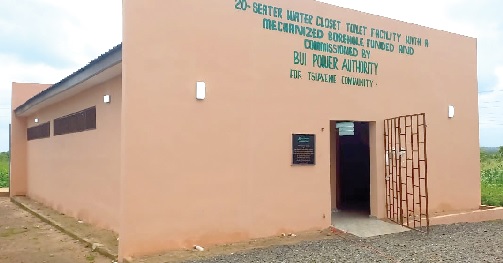 Samuel Kofi Ahiave Dzamesi (left), CEO of Bui Power Authority, being assisted to inaugurate the facility. INSET: The 20-seater water closet facility