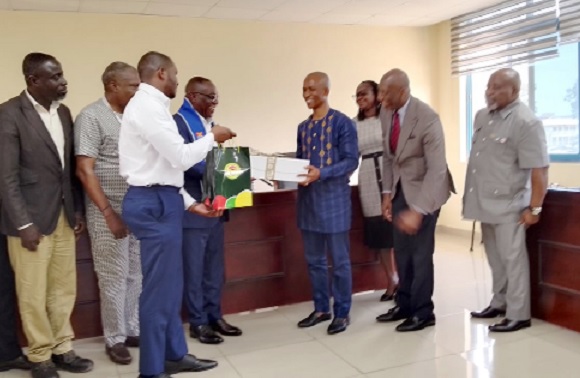 Kwasi Agyeman Busia (4th from left), CEO of DVLA, exchanging a souvenir with Prof. Martins Ekor, Provost of the College of Health and Allied Sciences of UCC. With them are officials of DVLA and UCC