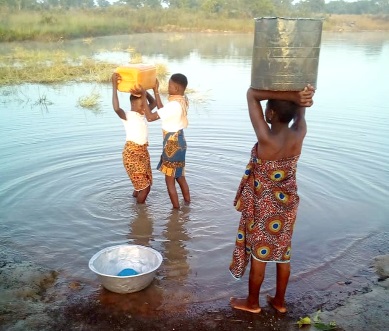 Some pupils fetching water from a dugout