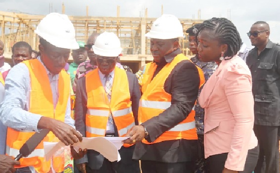 Yaw Osafo-Maafo (2nd from left), Senior Presidential Advisor; Akwasi Acquah (3rd from left), MP, and Victoria Adu (right), MCE, listening to the contractor as he briefs them on progress of the project