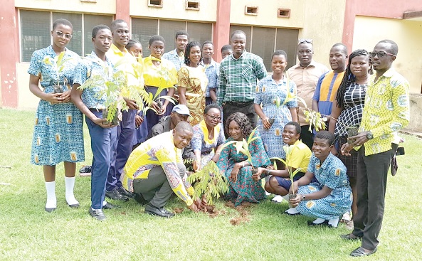 David Amevor (squatting left), the Koforidua Area Manager of ASA Savings and Loans; Elizabeth Ama Agyakwa (3rd from right), Headmistress of the Suhum Senior High Technical School, planting a seedling. Looking on are some students holding tree seedlings to also plant on the school's compound 