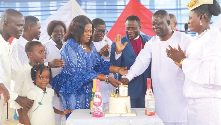 Emmanuel Adu-Gyamerah (2nd from right) being assisted by family and friends to cut his 60th birthday cake