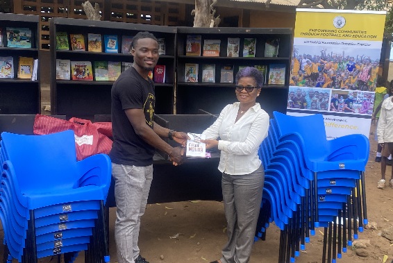 Hans Nunoo Sarpei (left) presenting a copy of the books to Madam Vincentia Korkuvi, 28th February Road &amp; Private Odartey Memorial Basic School