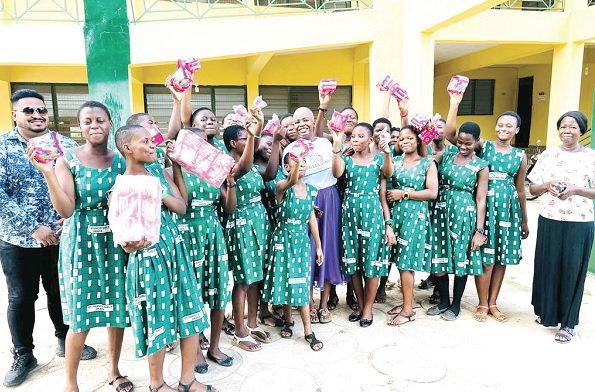 Some of the pupils displaying their sanitary pads. With them are Basil David Anthony  (left), CEO, Modern Floor Ghana, and Portia Gana, Founder, Portia Gana Foundation (right)