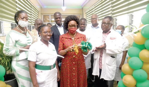 • Dr Eunice Brookman-Amissah (with scissors) cutting the tape to open the refurbished wards. With her are Kate Quartey-Papafio (left), some members of the foundation and staff of the hospital