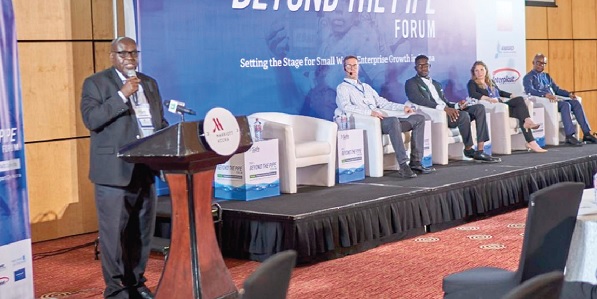 • Charles Nimako (left), Safe Water Network Ghana Country Director,  delivering his opening remarks at the forum. On the stage from left are Brett Gleitsmann, Programme Officer for the Conrad N. Hilton Foundation; Sylvester Adjapong, Regional Director for 4WARD Development West Africa; Lauren Cuscuna, Senior Manager, Innovations & MEL at Safe Water Network,  and  Harold Esseku, Senior WASH Specialist at the World Bank