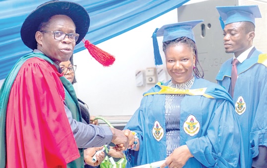 • Rev. Prof. Yaw Adu Gyamfi (left), Dean of Graduate Studies, CSUC, presenting a certificate to one of the graduates