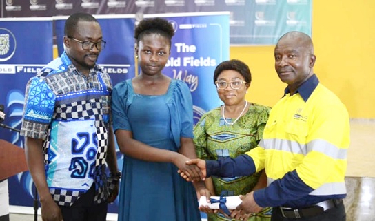 Judith Reese Obeng (left), a beneficiary, receiving her package from Robert Siaw (right), Regional Manager, Community Relations, Gold Fields, Tarkwa Mine. Looking on is Theodora Oduro (middle), Senior Assistant Registrar, Directorates of Students Affairs, KNUST