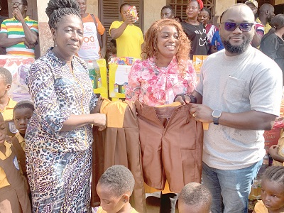Valentino Nii Noi Nortey (right), Founder, Nii Noi Nortey Foundation, presenting one of the uniforms to Joyce Osae-Apenteng (left), Municipal  Director of Education, Korle Klottey 