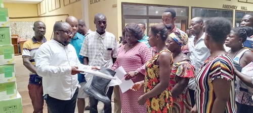 Solomon Ebo Appiah (left), Municipal Chief Executive for KEEA, handing over farm inputs to some farmers in the municipality. With them is Victoria Abankwa, the Municipal Director of Agriculture