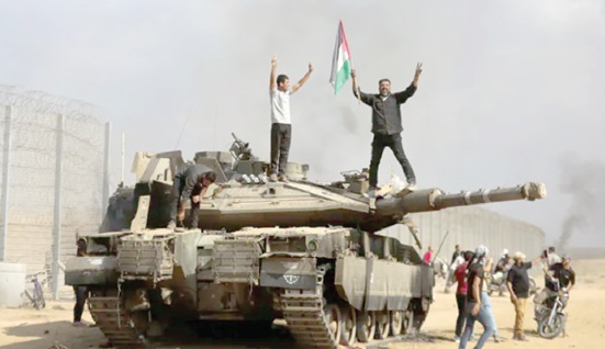 Palestinians waving their national flag and celebrating the destruction of the Israeli tank at the Gaza Strip fence east of Khan Younis 