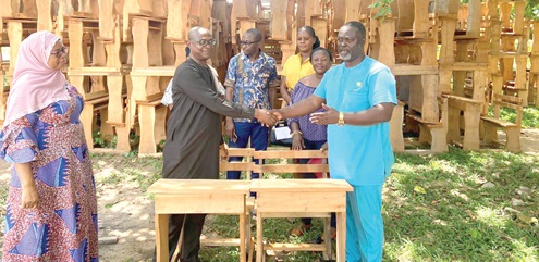 Isaac Appaw-Gyasi (right), Municipal Chief Executive for New Juaben South, presenting the furniture to Mustapha Haruna Appiah (left), New Juaben South Municipal Education Director. Looking on are other dignitaries