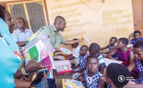 Dr Eric Nkansah (right), Director-General of GES, distributing learning materials to some pupils