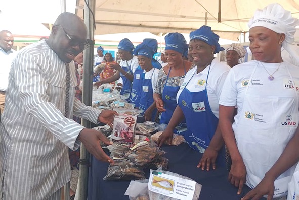 Moses Anim (left), Deputy Minister of Fisheries and Aquaculture Development,  interacting with some fish processors at the exhibition stand during the opening of the fish festival
