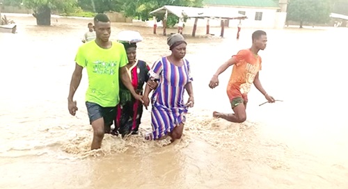 Some residents in the North-East Region wading through floodwater