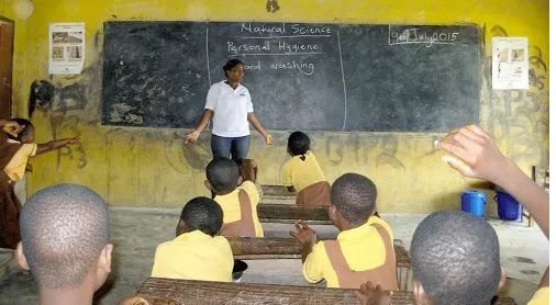 A teacher in a classroom with pupils listening attentively