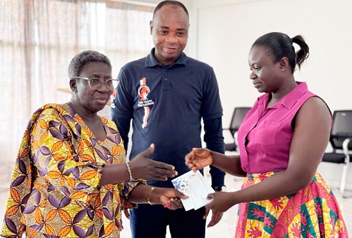 Comfort Asante (left), the Municipal Chief Executive of New Juabeng North, presenting the training fee to Rebecca Korantengmah, one of the craftswomen, while Bright Appiah, the Executive Director of CRI looks on
