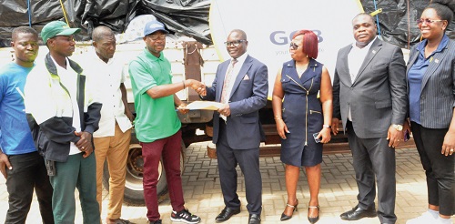  John Adamah (4th from right), GCB PLC’s Executive Head, Retail Banking, handing over some of the relief items to Divine Osborn Fenu (4th from left), the DCE of North Tongu. With them are some officials of the bank and the district assembly