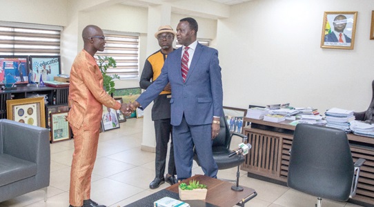 Dr Yaw Osei Adutwum (right), Minister of Education, in a handshake with Eric Asomani Asante, the 2020 National Best Teacher. With them is Dr Christian Addai-Poku (slightly covered), Registrar, National Teaching Council