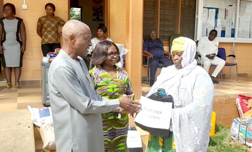 Alhaji Umar Baba Bodinga (left), Municipal Chief Executive for Abuakwa North, presenting polythene bags to Mariama Gariba, one of the beneficiaries