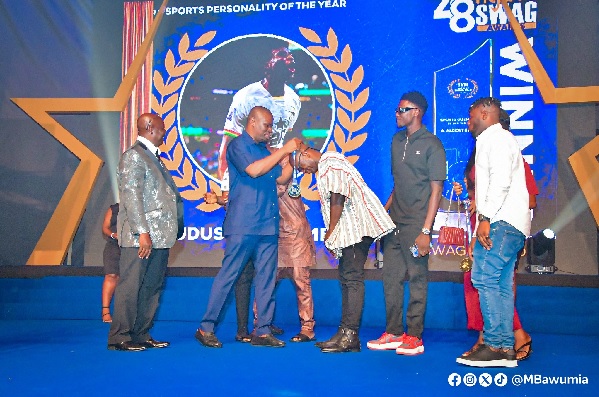Mr Mustapha Yusif, Minister of Youth and Sports presenting the award to a relative of Kudus Mohammed while Mr Kwabena Yeboah (left), SWAG President looks on